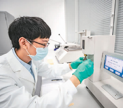  在重慶三峽文物科技保護基地內，“文物醫生”運用各種“診療”設備對手里的文物進行精準治療，讓其煥發出新的活力。   圖為2022年，“文物醫生”利用耐折度儀對紙張的耐折度進行測試。   新華社記者 黃 偉攝