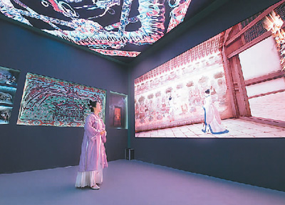 第十九屆中國（深圳）國際文化產業博覽交易會設立了“數字中國——AI時代的文化創新”主題展區。一批大數據、人工智能等技術應用文化企業參展。數字化助力中華傳統文化“活”起來，也為現場觀眾帶來了新鮮的觀展體驗。   圖為一名身著傳統服飾的觀眾在文博會甘肅展臺觀看數字敦煌展覽。   新華社記者 梁 旭攝