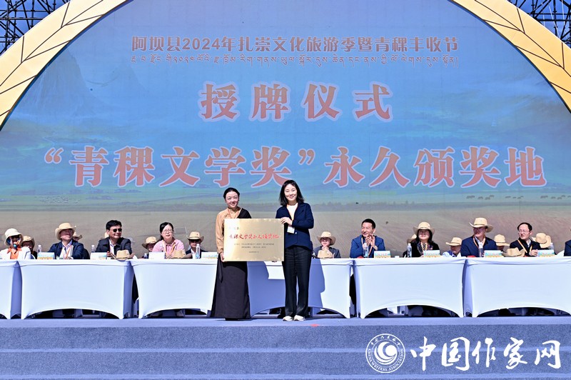 陳亞軍主編代表《民族文學》向阿壩縣授牌，紅梅部長接牌。