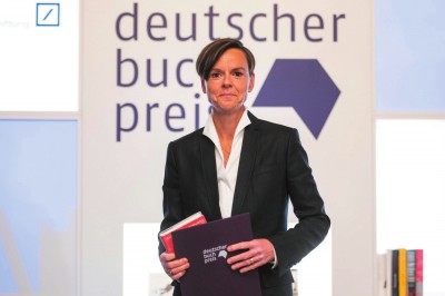     作家安特耶·拉維克·施特魯貝爾在2021年德國圖書獎頒獎典禮上手持《藍色女人》和獲獎證書。攝影：托馬斯·洛內斯